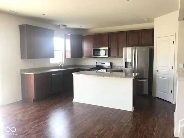 kitchen featuring appliances with stainless steel finishes, sink, dark hardwood / wood-style flooring, a center island, and dark brown cabinetry