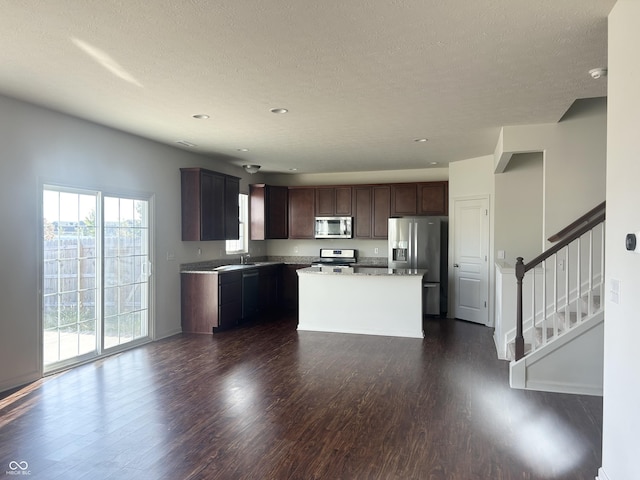 kitchen featuring appliances with stainless steel finishes, sink, dark hardwood / wood-style flooring, a center island, and dark brown cabinetry