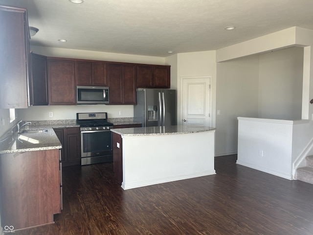 kitchen with sink, a kitchen island, dark hardwood / wood-style floors, and appliances with stainless steel finishes