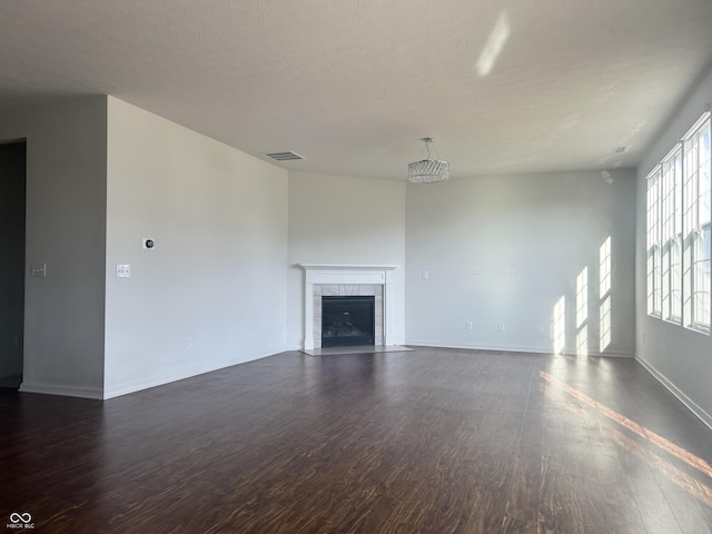 unfurnished living room with a tiled fireplace and dark hardwood / wood-style floors