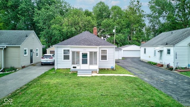 bungalow-style home featuring a front lawn, an outdoor structure, and a garage