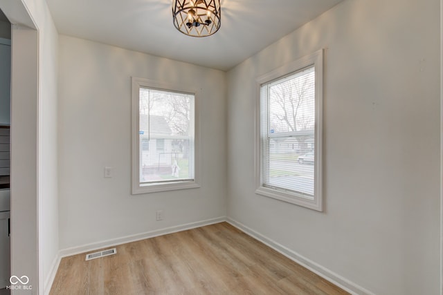 spare room with an inviting chandelier and light hardwood / wood-style flooring