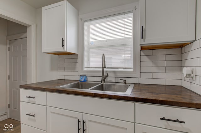 kitchen with tasteful backsplash, white cabinetry, and sink