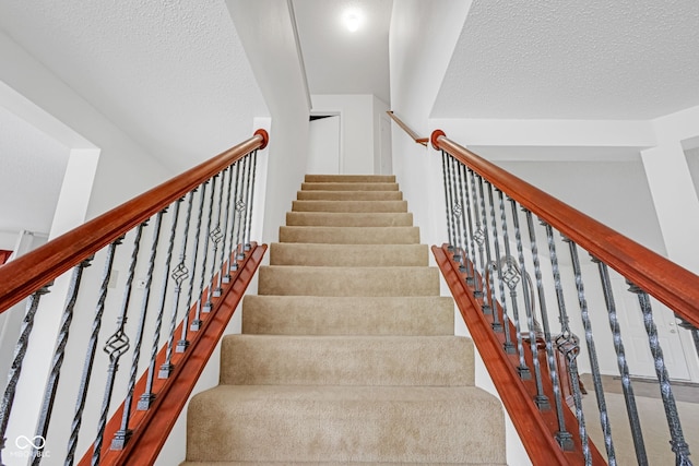 stairway featuring a textured ceiling