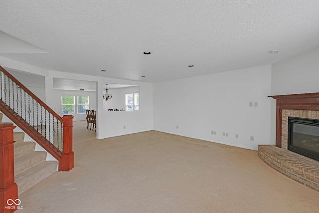 unfurnished living room featuring an inviting chandelier, light carpet, and a textured ceiling