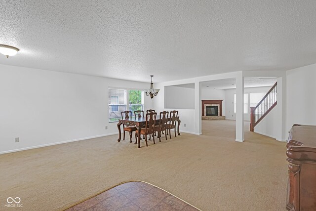 carpeted dining area with an inviting chandelier, a textured ceiling, and a fireplace