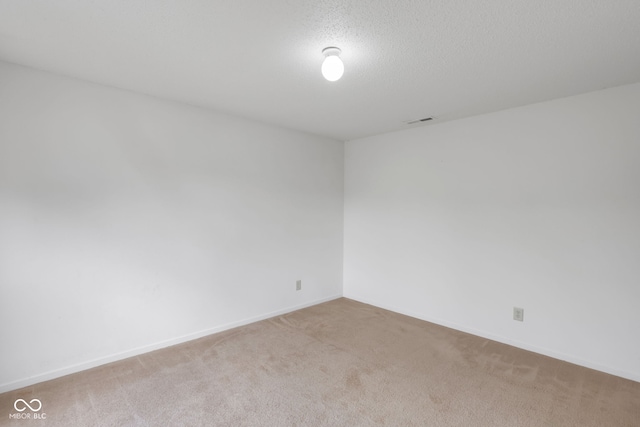 carpeted empty room featuring a textured ceiling