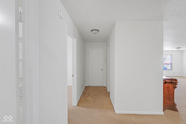 hall with light carpet and a textured ceiling