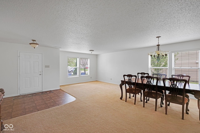 carpeted dining area featuring a notable chandelier and a textured ceiling