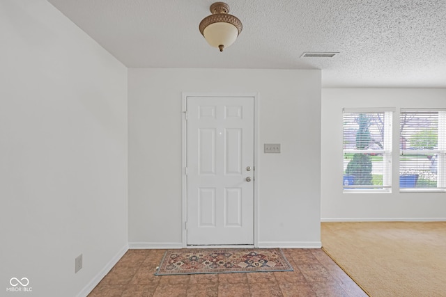 carpeted entrance foyer featuring a textured ceiling