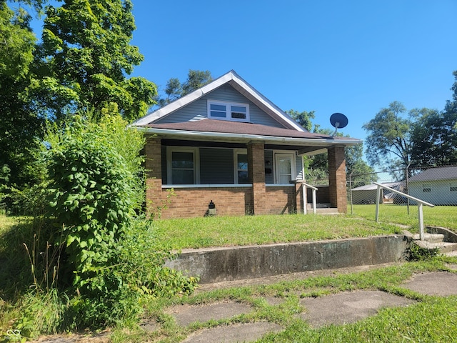 2221 Langley Ave, Indianapolis, IN 46218 - bungalow-style home with brick siding, a front lawn, and covered porch