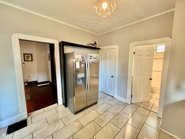 kitchen with stainless steel refrigerator with ice dispenser, a textured ceiling, ornamental molding, and light tile patterned floors