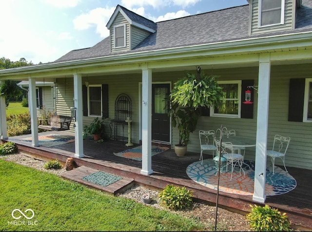 doorway to property with a shingled roof and a porch