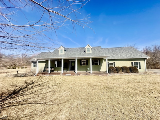 back of property featuring a yard, a porch, and roof with shingles