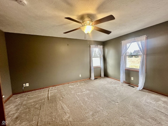 carpeted empty room with baseboards, visible vents, ceiling fan, and a textured ceiling