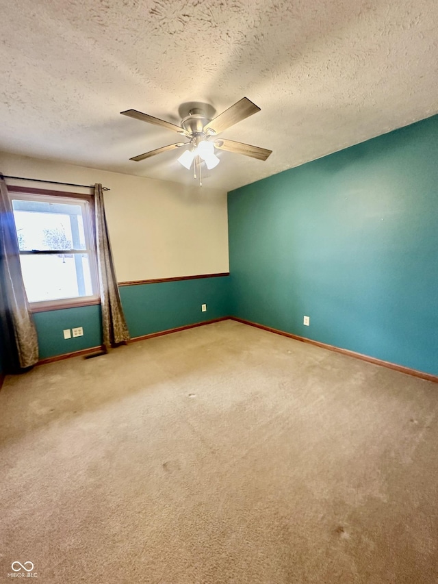 empty room featuring a ceiling fan, a textured ceiling, baseboards, and carpet flooring