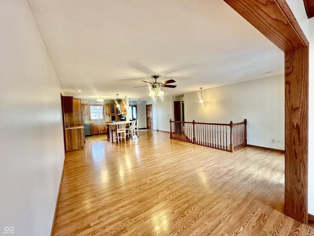 spare room with baseboards, ceiling fan, and light wood finished floors