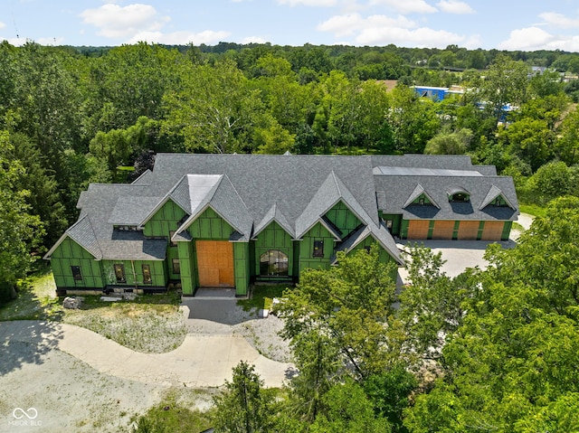 view of front of property with a wooded view and roof with shingles