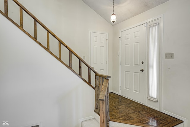 foyer entrance with parquet floors and vaulted ceiling