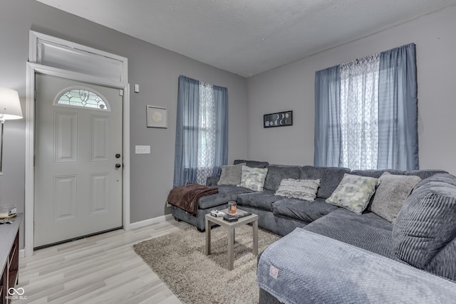 living room featuring a textured ceiling, light hardwood / wood-style floors, and a healthy amount of sunlight