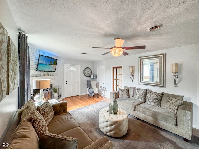 living room featuring a textured ceiling, ceiling fan, and light hardwood / wood-style floors