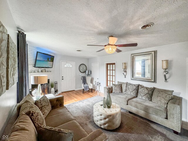 5647 W Mooresville Rd, Indianapolis, IN 46221 - living room with wood-type flooring, a brick fireplace, ceiling fan, and a textured ceiling