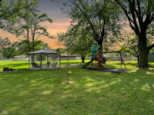 yard at dusk featuring a playground and a gazebo