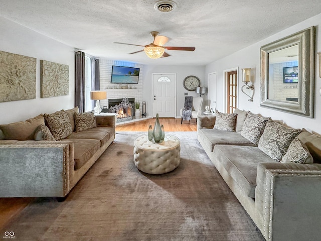 5647 W Mooresville Rd, Indianapolis, IN 46221 - living room with ceiling fan, a brick fireplace, dark hardwood / wood-style floors, and a textured ceiling
