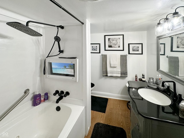 bathroom with a textured ceiling, vanity, wood-type flooring, and a bathing tub