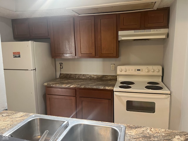 kitchen with sink, light stone counters, and white appliances