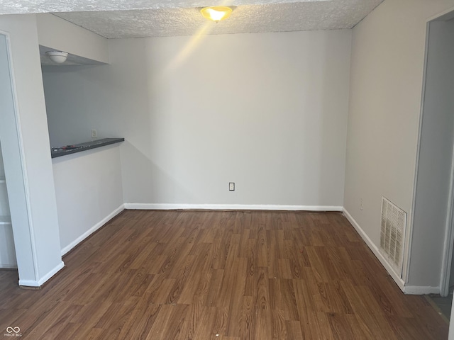 unfurnished room featuring dark wood-type flooring and a textured ceiling