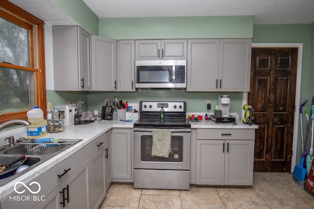 kitchen featuring sink, appliances with stainless steel finishes, gray cabinets, and light tile patterned floors