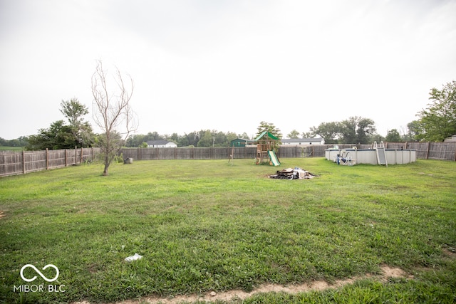 view of yard with a playground and a fenced in pool