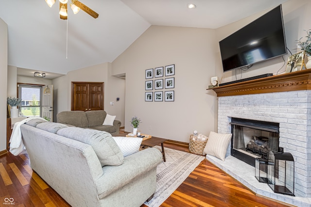 living room with a brick fireplace, ceiling fan, vaulted ceiling, and hardwood / wood-style flooring