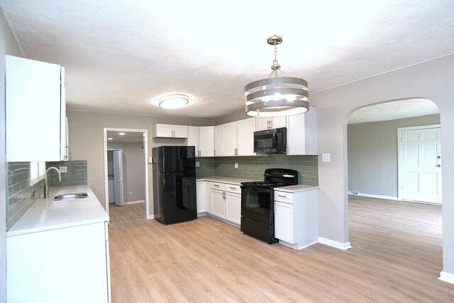 kitchen featuring white cabinets, pendant lighting, black appliances, light hardwood / wood-style floors, and sink