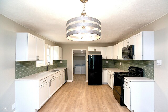 kitchen featuring pendant lighting, washing machine and dryer, tasteful backsplash, black appliances, and light hardwood / wood-style flooring