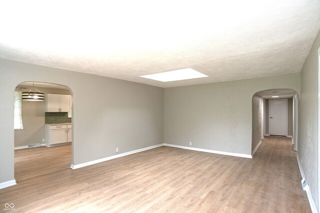 empty room with light hardwood / wood-style flooring and a skylight