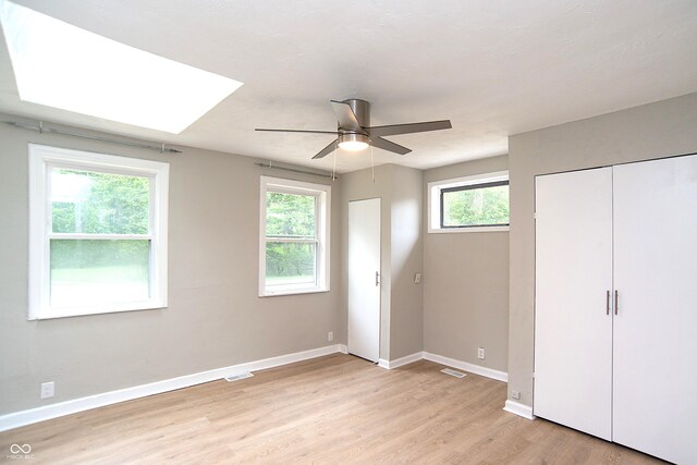 unfurnished bedroom featuring ceiling fan, multiple windows, and light hardwood / wood-style floors