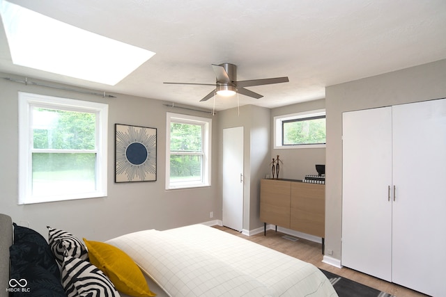 bedroom with ceiling fan, light hardwood / wood-style flooring, and multiple windows