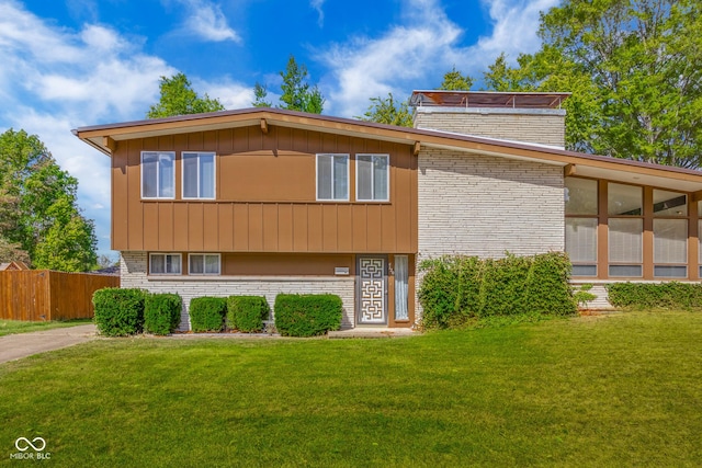 view of front of property featuring a front lawn, fence, and brick siding