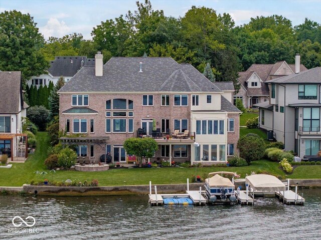 rear view of property with a water view, a yard, and a balcony