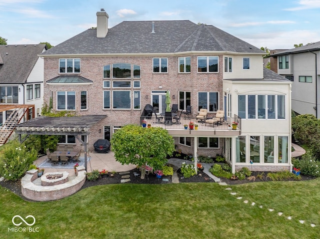 rear view of property featuring a patio, a yard, a fire pit, a wooden deck, and a pergola