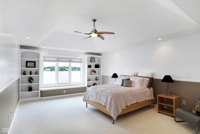 carpeted bedroom featuring ceiling fan and a raised ceiling