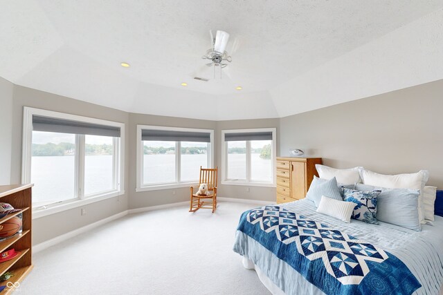 bedroom with light colored carpet, multiple windows, vaulted ceiling, and a water view