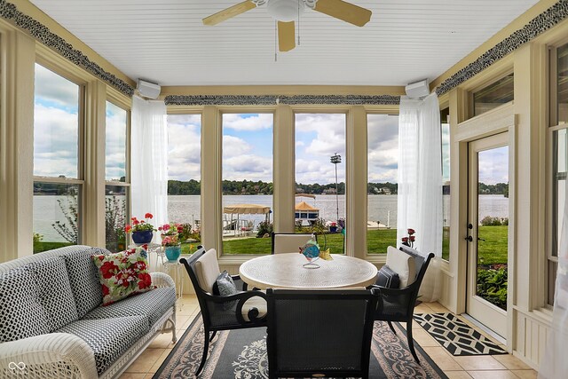 sunroom with ceiling fan, a water view, and a healthy amount of sunlight