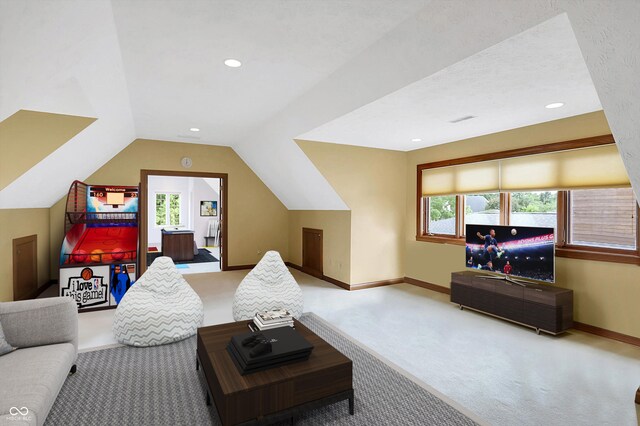 living room with lofted ceiling, a textured ceiling, light colored carpet, and a healthy amount of sunlight