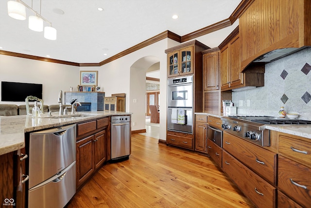 kitchen featuring light stone counters, sink, light hardwood / wood-style flooring, appliances with stainless steel finishes, and decorative light fixtures