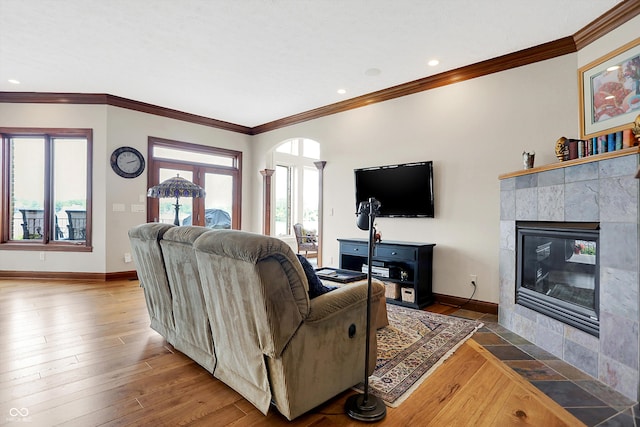 living room with crown molding, a tiled fireplace, and hardwood / wood-style floors