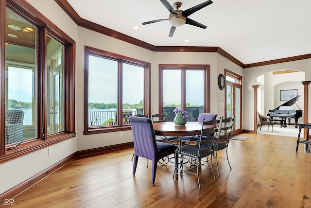 dining space featuring light wood-type flooring, crown molding, and a healthy amount of sunlight