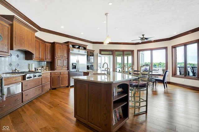 kitchen with appliances with stainless steel finishes, dark hardwood / wood-style floors, a kitchen island with sink, and sink